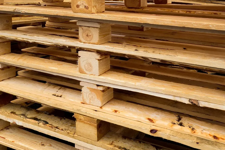 A close, low view of stacked pale wooden pallets