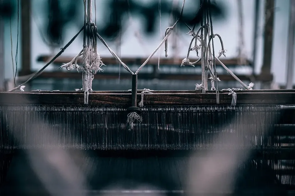 Threads strung across an old weaving loom inside a dim textile workshop